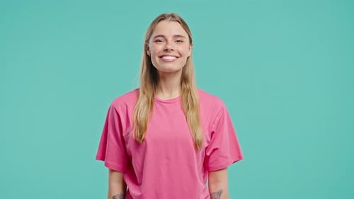 Smiling young woman in pink shirt on blue background