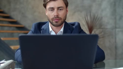 Serious businessman typing on laptop in private office in slow motion