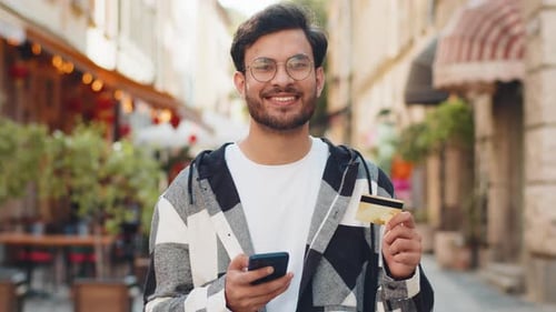 Man Using Phone and Credit Card on City Street