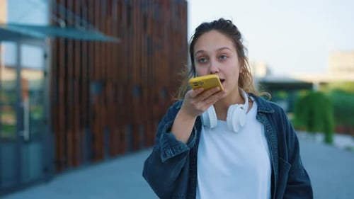 Young Woman Recording Voice Message on Cell Phone