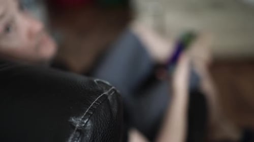 Person Using Phone While Relaxing on Couch Indoors