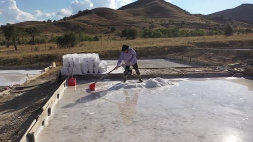 Aerial View Of Worker Working In Salt Production Ponds In Mountain