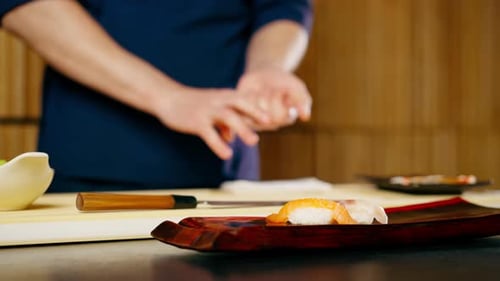 Closeup in Japanese Restaurant the Chef Lays Out Pieces of Raw Fish on a Plate