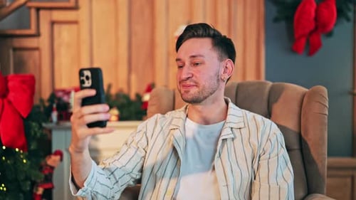 Man video chats holding phone in decorated home