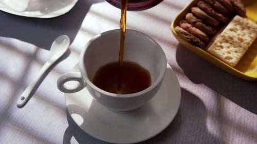 Pouring Coffee into Cup with Cookies and Crackers