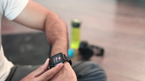 Sporty Man Checking Pulse on Smartwatch After Workout Inside