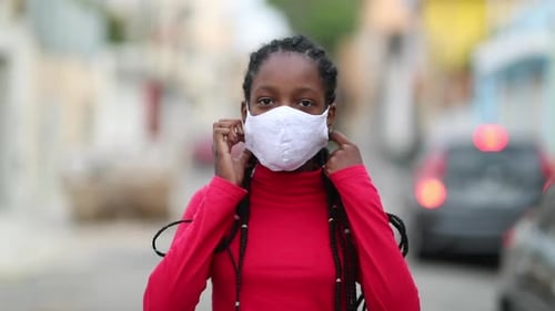 Niña africana negra que se quita la máscara facial contra el covid-19 sintiendo alivio