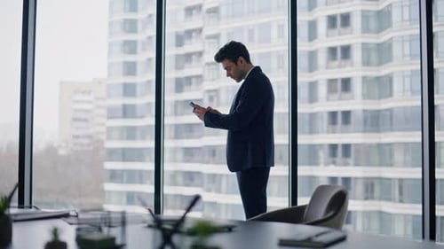 Shocked Employee Receiving Smartphone Message By Office Panoramic Window