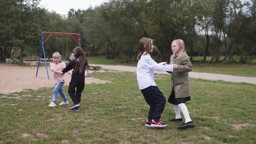 Joyful Little Girls Playing in a Spring or Summer or Autumn Park in Their City