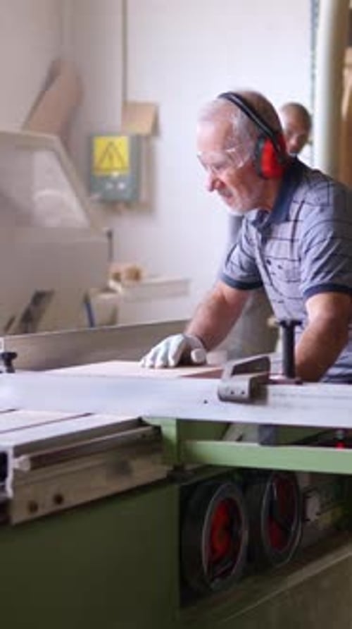 Man Cutting Wood with Saw in Workshop Environment
