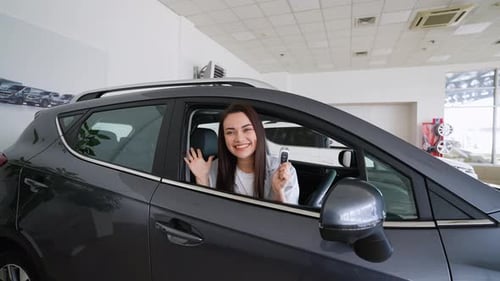 Happy Woman Holding Keys to Her New Car at the Dealership Right Hand Drive Car