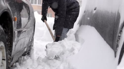 Physically demanding task of removing hardened snow from narrow parking gap