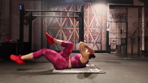 Woman does bicycle crunch exercise in a gym