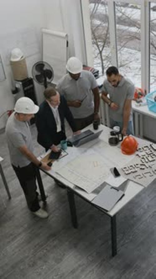 Multicultural Construction Workers Analyzing Blueprints in Office