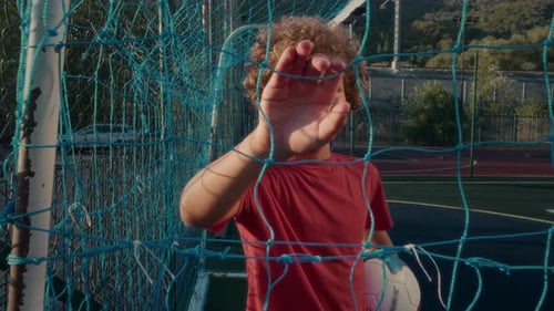Boy Smiling in Soccer Net Holding Ball