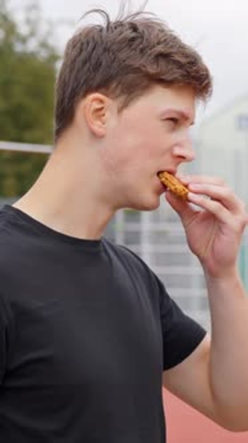 An athlete takes a break to eat a dietary snack; vertical footage