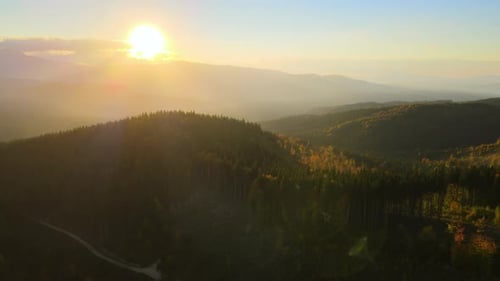 Beautiful Evening Panoramic Landscape with Bright Setting Sun Over Distant Mountain Peaks at Sunset