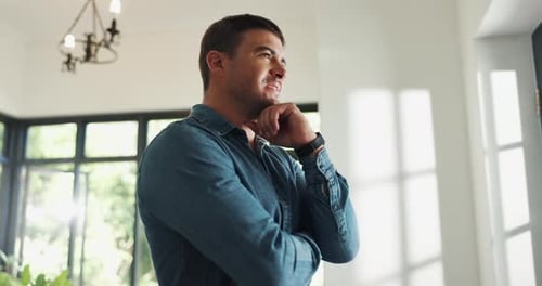 Pensive Man Standing Inside Sunlit Home Near Window