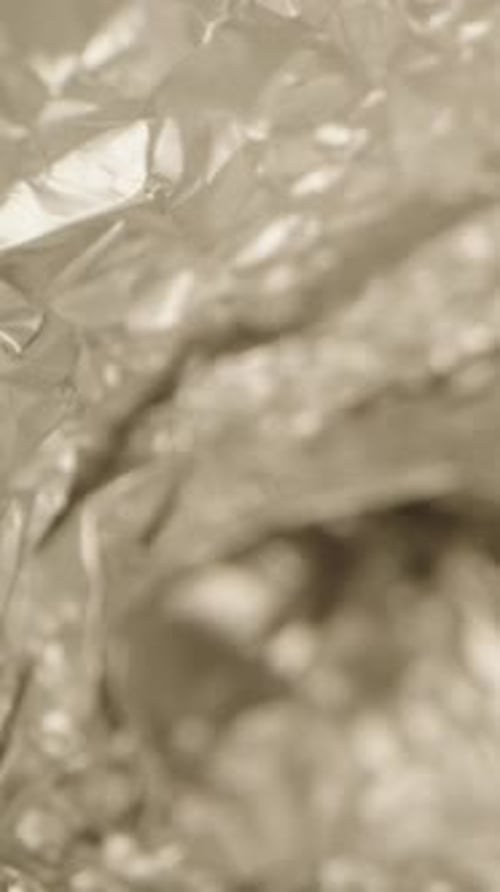 Vertical video. Textured Kitchen aluminum glitter foil. probe lens. Reflection. Dolly slider macro