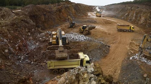 Bagger gießt Erde in Muldenkipper