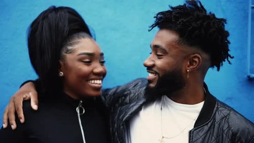 Affectionate Young Couple Smiling Together Near Blue Wall