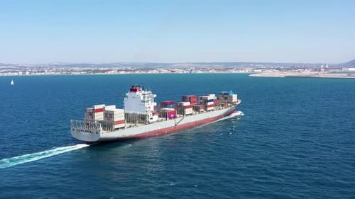 Aerial footage of a container ship approaching a commercial port.
