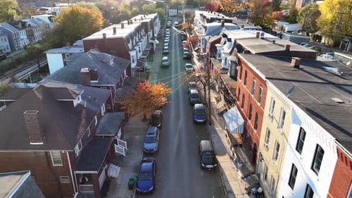 Urban housing in American city during autumn. Aerial establishing shot above old rowhouses during su