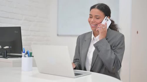Woman at Desk Talking on Mobile Phone
