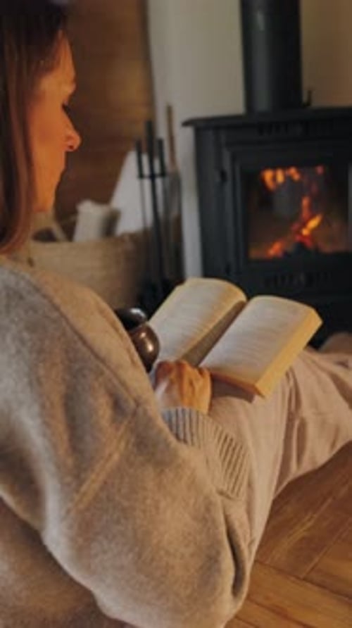 Woman Reading by Fireplace in Cozy Indoor Setting