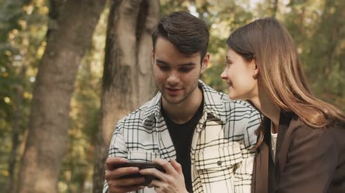 Young Couple Looking at Smartphone Outdoors Together