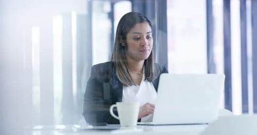4k-Videomaterial einer jungen Geschäftsfrau, die in einem Büro an einem Laptop arbeitet