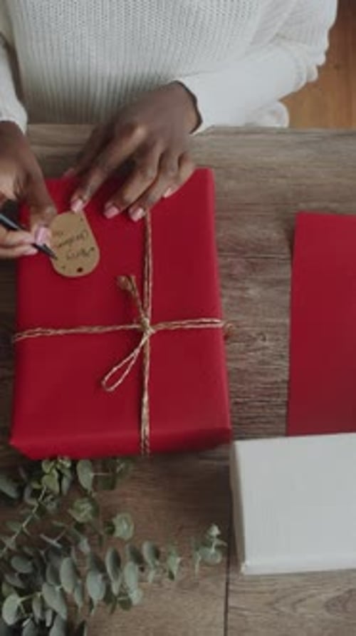 Hands Wrap Christmas Gift with Bright Red Paper