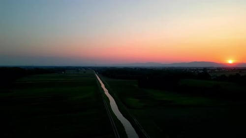 Aerial Panoramic View Of Calm River And Fields At Sunset - drone shot