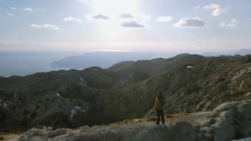 Fly over man standing on ridge looking to idyllic mountain and sea view, Sveti Jure, Croatia. Aerial
