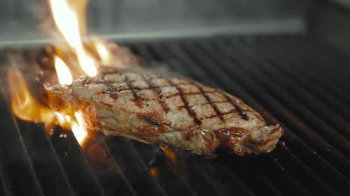Close-Up of Steak Cooking on Grill with Flames