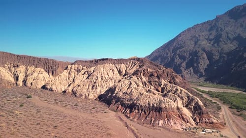 Aerial view drone flying over scenic rocky mountains landscape with a clear blue sky.
