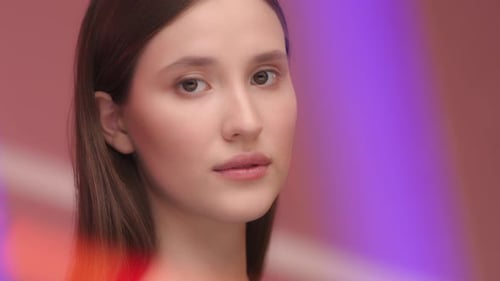 Beautiful young woman's face illuminated by vibrant neon lights in a modern portrait