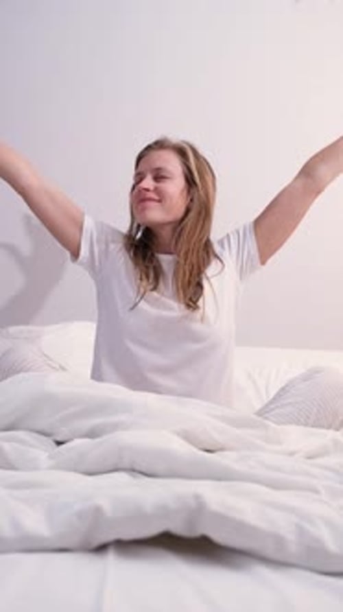 Young Woman Stretching and Yawning in Bed