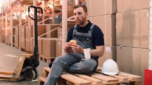 Lunch time. Eating and drinking. Storage worker in uniform is in the warehouse