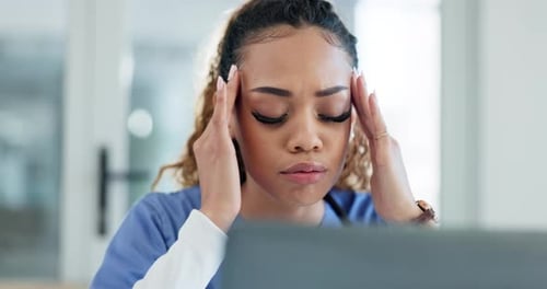Tired Woman in Scrubs with Hands on Head