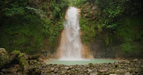 Majestic Blue Falls waterfall cascades into a turquoise pool surrounded by lush jungle in Costa Rica