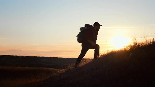 Man Hiking on the Edge of the Mountain As a Silhouette in Colorful Sunset