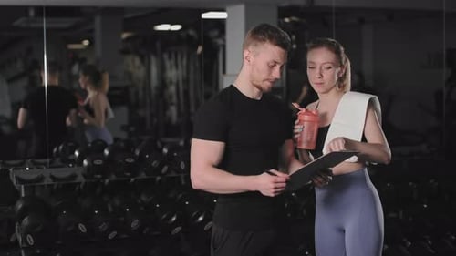 Trainer and Client Reviewing Workout Plan in Gym