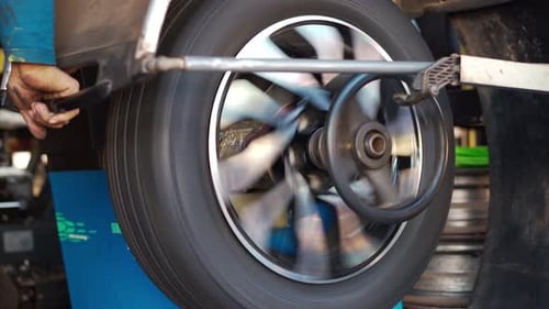mechanic man balancing a car wheel on an automated machine