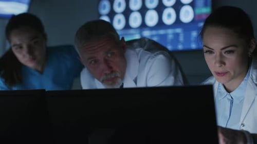 Diverse Team of Medical Scientists Solve Problems and Point at Computer Screens Showing CT, MRI Sca