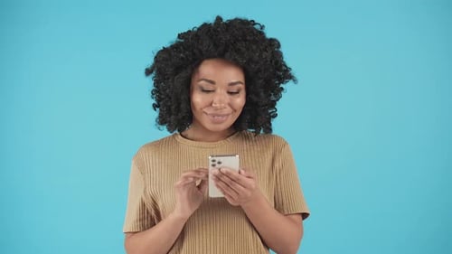A Pretty Black Woman Looks at Something on Her Smartphone Then Looks at the Camera and Gives a