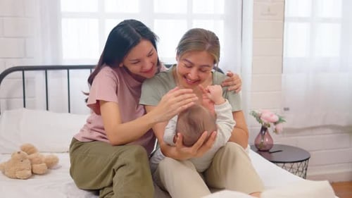 Asian lesbian couple caring for and raising their baby boy at home.