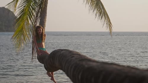 Girl On A Palm Tree With The Sea Behind