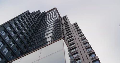 Skyscraper against cloudy sky, low angle view. Camera panning left
