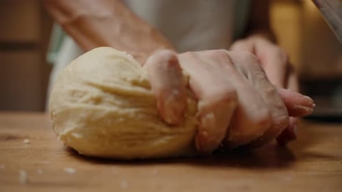 Close Up of Hands Kneading Dough on Wood